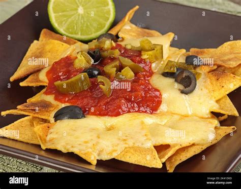 crisp cheesy nachos wit tomato salsa olives and jalapenos Stock Photo ...