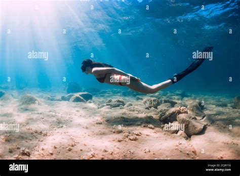 Freediver Slim Woman In Bikini Glides In Blue Sea And Sun Rays