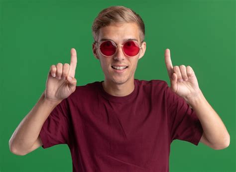 Sonriente Joven Guapo Con Camisa Roja Y Gafas Apunta Hacia Arriba