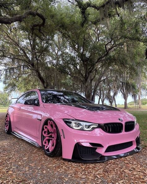 A Pink Car Parked In Front Of Some Trees