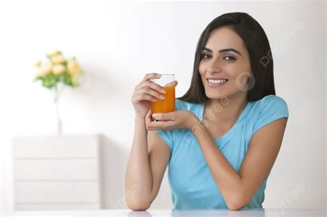 Portrait Of Beautiful Young Woman Holding Glass Of Orange Juice At Home