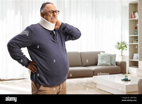 Mature Man In Pain Wearing A Cervical Collar And Holding His Neck At