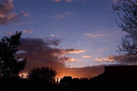 Golden Sunset Behind Silhouetted British Homes And Trees With Scattered