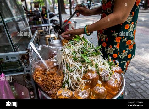 A Street Food Cook Adds Final Condiments To An Entree On Saigon Street