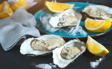 Fresh Oysters Closeup On Blue Plate Served Table With Oysters Lemon And Ice Healthy Sea Food