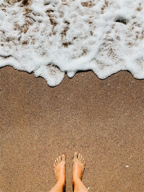 Pernas De Mulher Com Os Pés Descalços Nas Ondas De Espuma Do Mar Na