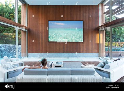 Woman watching large flat screen TV in modern living room Stock Photo - Alamy