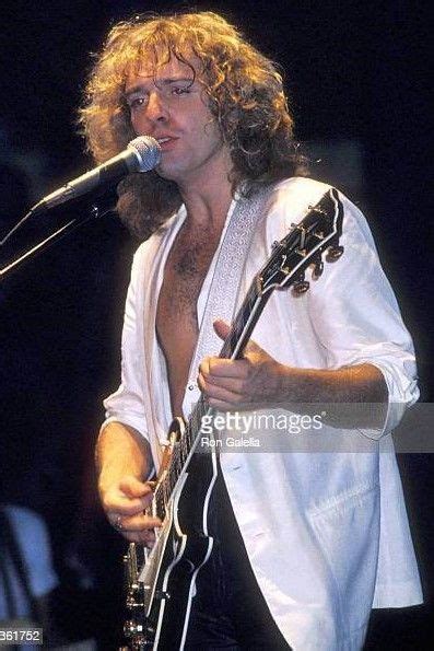 A Man With Long Hair And No Shirt Playing An Electric Guitar In Front