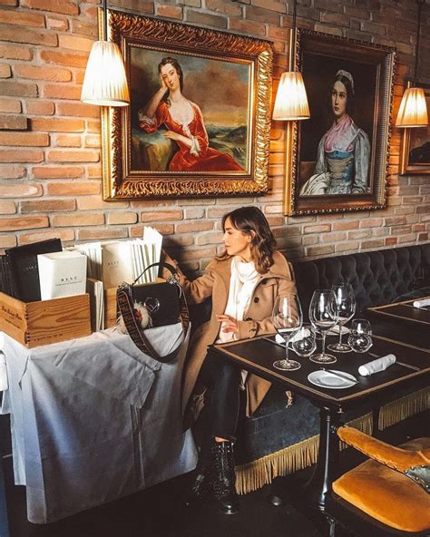 A Woman Sitting At A Table In A Restaurant Next To A Painting On The Wall