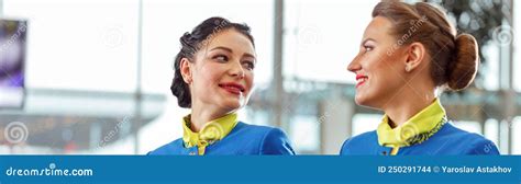 Two Flight Attendants Walking Arm In Arm At Airport Terminal Stock