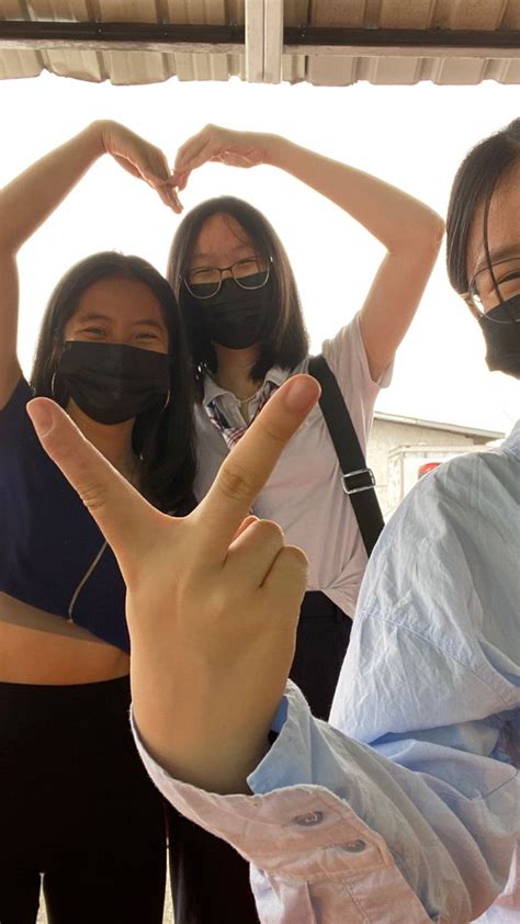 three women wearing face masks making the shape of a v with their hands ...