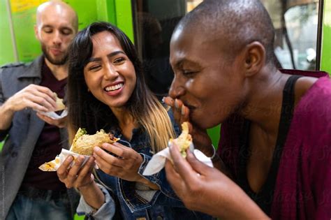 Woman Eats Taco With Friends By Stocksy Contributor Jayme Burrows