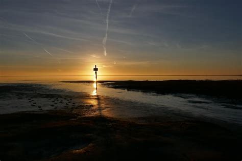 Silhueta de um farol no mar contra o céu durante o pôr do sol Foto