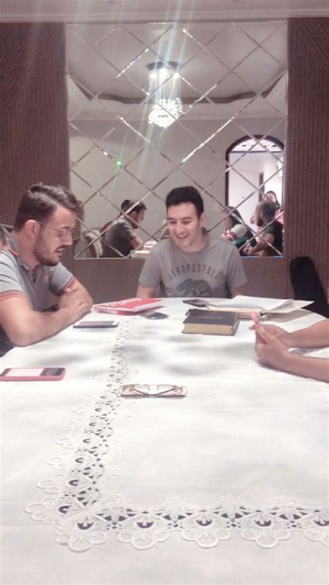 Two Men Sitting At A Table With Cards And Papers On It While Another