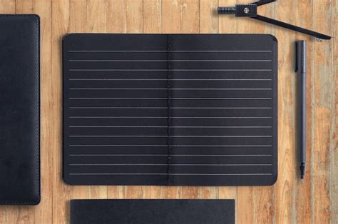 Cuaderno Y Pluma Negros En Blanco En El Fondo De Madera Foto Premium