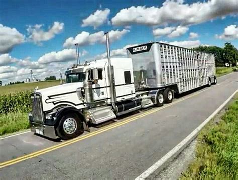 A Semi Truck Driving Down The Road In Front Of A Cornfield With Blue