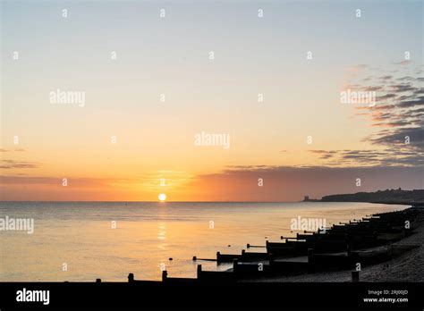 Sunrise Over The Sea Seen From The Beach With Wooden Wave Breakers Aka