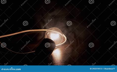 One Glowing Incandescent Light Bulb With A Wire Lies On A Wooden Table