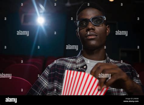 Concentrated Man Having Popcorn While Watching Movie In Theatre Stock