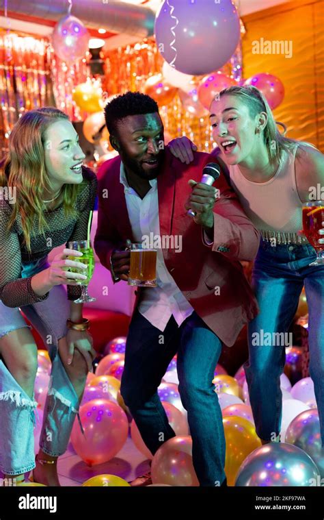 Vertical Of Three Happy Diverse Male And Female Friends Singing