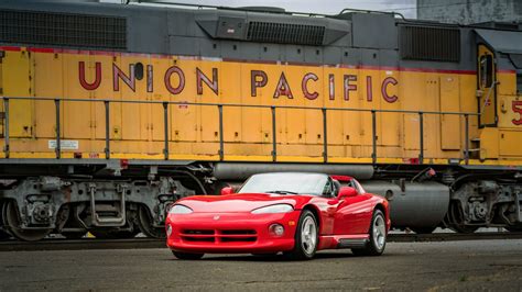 a red sports car is parked in front of a train with union pacific written on it