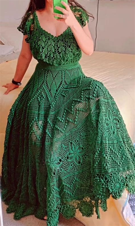 A Woman In A Green Dress Taking A Selfie With Her Cell Phone While