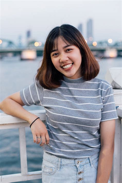 Happy Thai Teenage Portrait By The Riverside In Bangkok By Stocksy