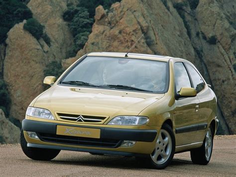 A Small Yellow Car Parked In Front Of Some Mountains