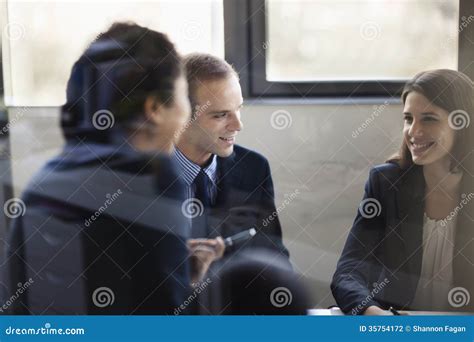 Three Business People Sitting And Discussing At A Business Meeting