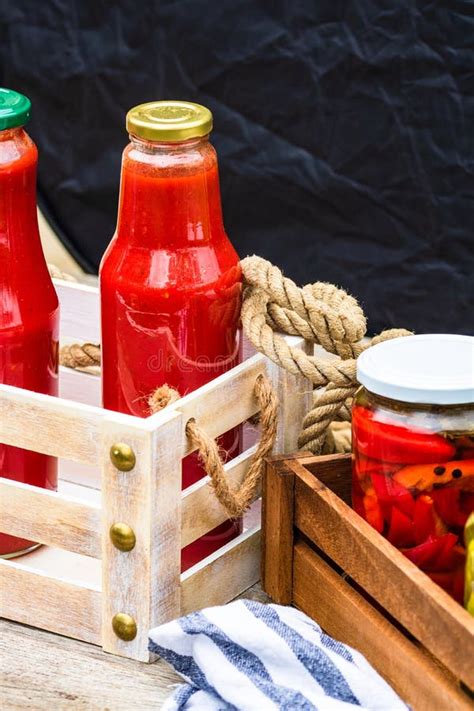 Glass Jars With Pickled Red Bell Peppers And Bottles With Tomatoes