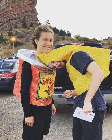 Two People In Costumes Standing Next To Each Other Near A Car And Rock