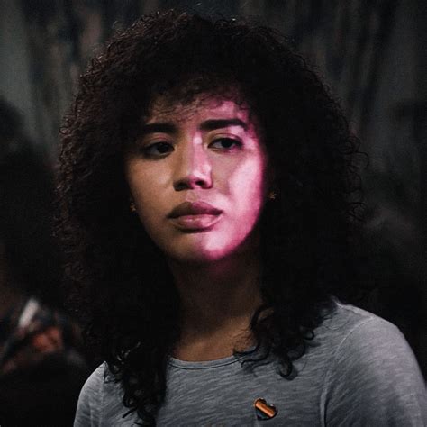 a close up of a person with dark hair and pink light on her face,