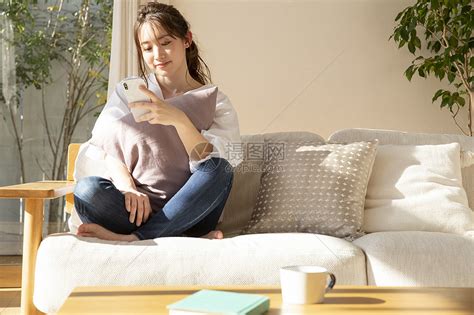 居家沙发玩手机的年轻女子高清图片下载 正版图片502333525 摄图网