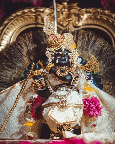 An Idol Is Displayed In Front Of A Gold And White Backdrop With Flowers