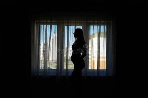 Silhouette Of Pregnant Woman Standing Near Window At Home Stock Image