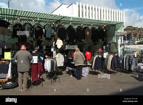 Shoppers Wearing Winter Coats At Market Stall Viewing Clothing For Sale