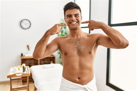 Young Hispanic Man Standing Shirtless At Spa Center Smiling Cheerful