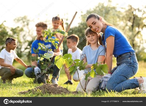 Niños plantando árboles con voluntarios en el parque fotografía de