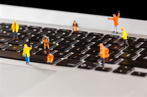 Free Photo | Miniature workmen repairing a laptop keyboard