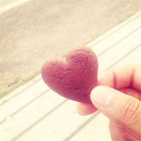 Dedos segurando um biscoito em forma de coração Foto Premium