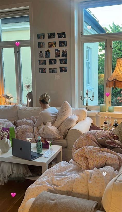 A Woman Sitting On Top Of A White Couch In A Living Room Filled With