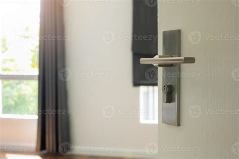 Modern door handle on white door with room interior 12811376 Stock