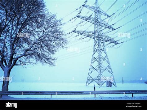 Snowfall In Winter Landscape With Tree And High Voltage Pylon Stock