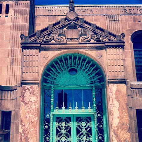 an old building with a large green door and ornate iron work on the front window