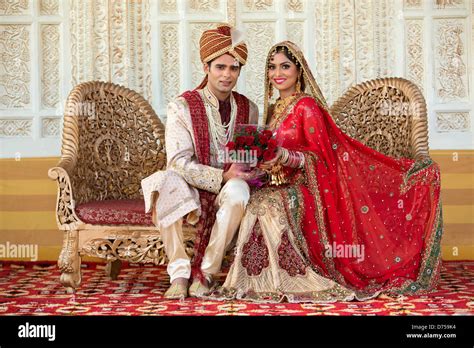 Indian Bride And Groom In Traditional Wedding Dress Sitting On A Couch