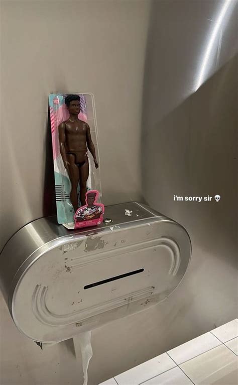 A Bathroom Stall With A Fake Naked Man On The Toilet Paper Dispenser