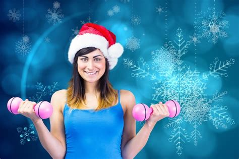 Premium Photo Festive Fit Brunette Holding Dumbbells Against Blue