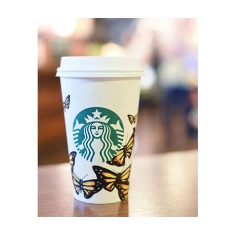 A Starbucks Cup With Butterflies On It Sitting On A Wooden Table In