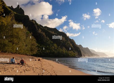 People At Kee Beach Watch Sunset Illuminate The Na Pali Coast On Kauai