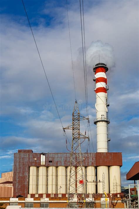 Factory Chimney And Abandoned Warehouse Against Blue Sky Stock Photo